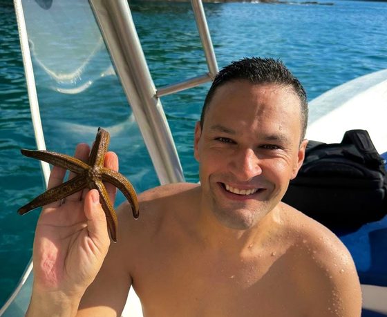 Juan Pablo holding a starfish on the boat